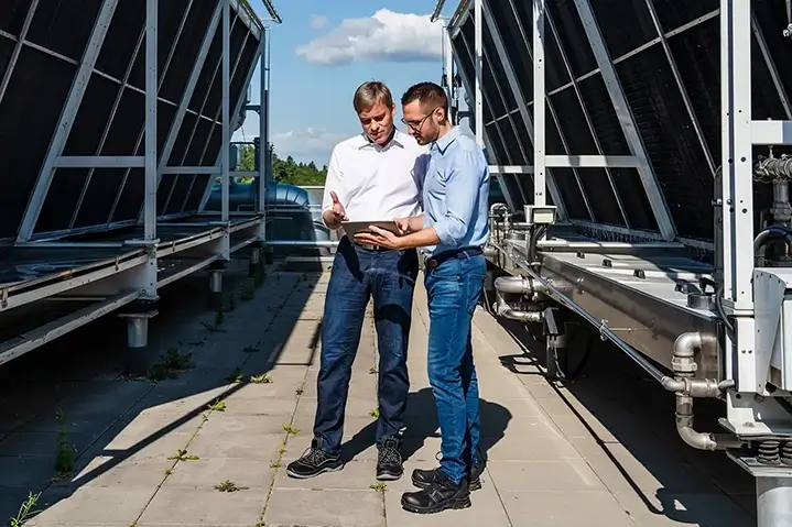 Two man doing some planning on a tablet in between 2 solar panels