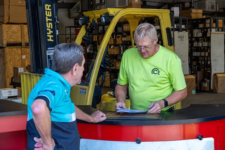 2 men discussing next to a yellow warehouse forklift